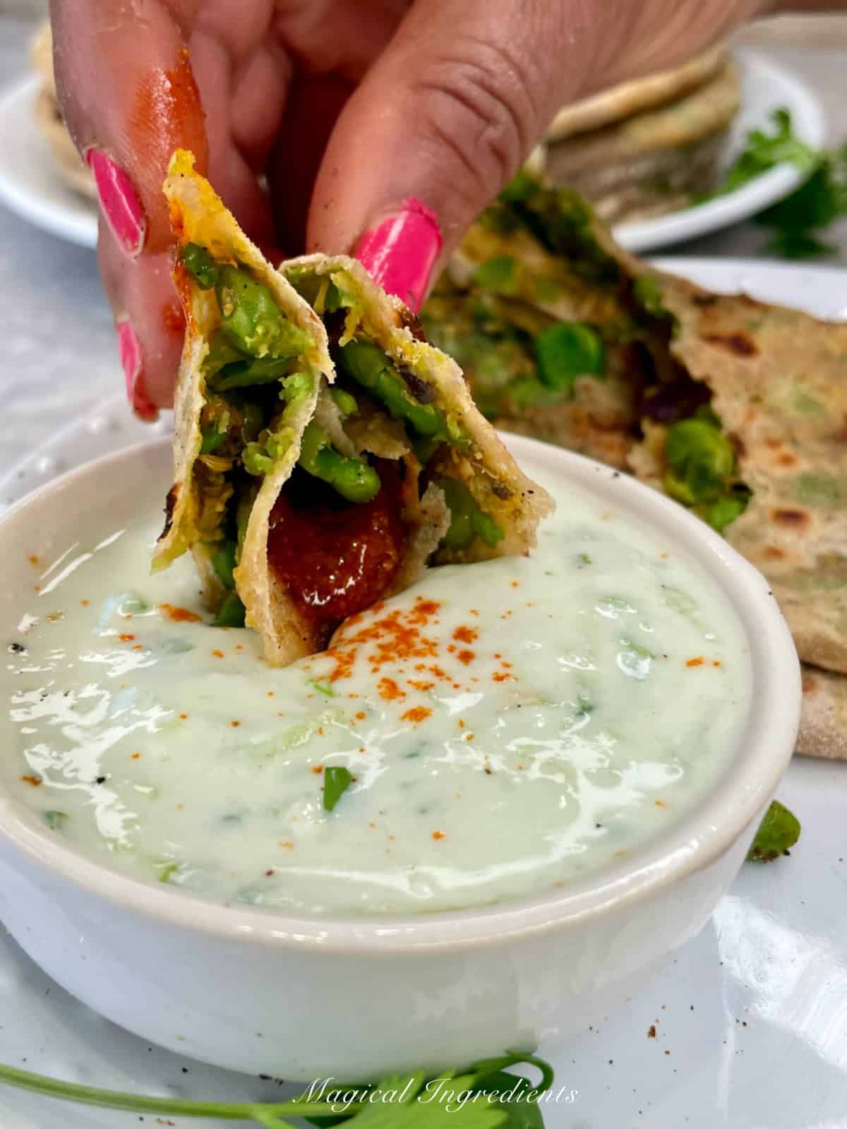 a close view showing the stuffing, dipping parathas with pickle and raita