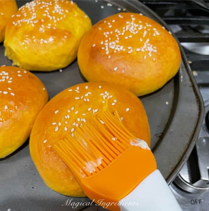brushing the buns with butter after baking